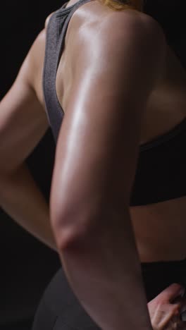 Vertical-Video-Close-Up-Studio-Shot-Showing-Back-Of-Mature-Woman-Wearing-Gym-Fitness-Clothing-Doing-Stretching-Exercises